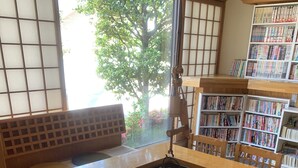 Ein traditioneller japanischer Raum mit Tatami-Bodenbelag, einem niedrigen Holztisch und einer Bücherwand.
