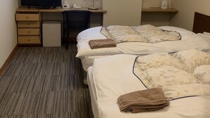 Ein Hotelzimmer mit zwei Betten, einem Schreibtisch mit Fernseher, einer Lampe und einem Fenster mit Blick.