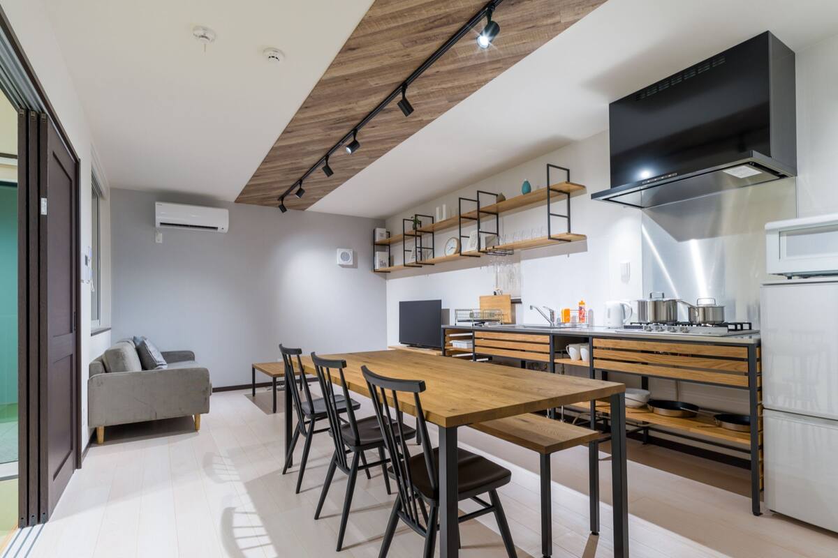 A modern kitchen with a wooden dining table, black chairs, and a built-in oven.