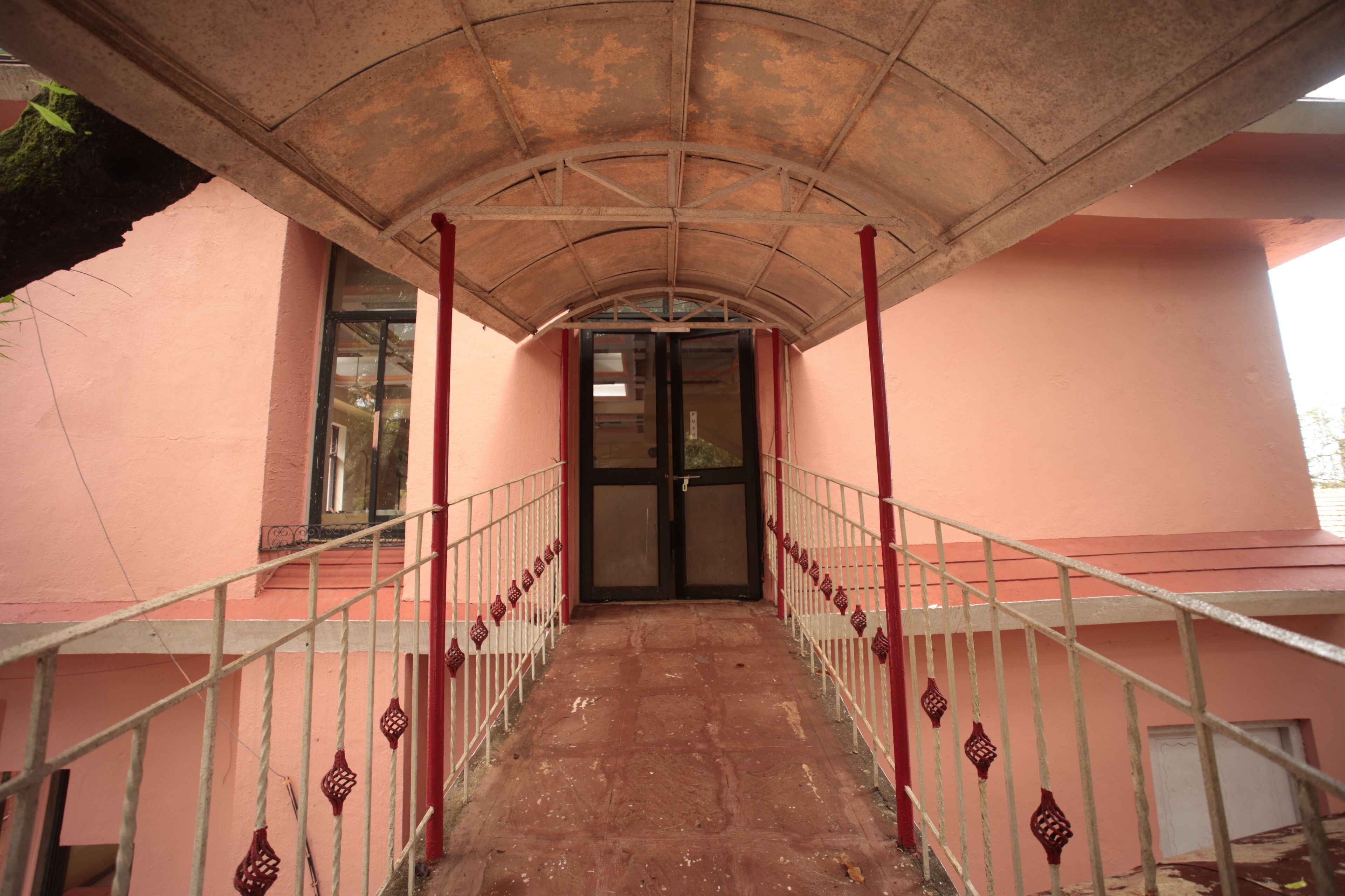 A corridor with a metal railing, a red and white color scheme, and a door at the end.