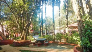 Une cour intérieure avec un espace de repos central, entourée d’arbres et de plantes en pot.