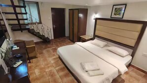 Une chambre à coucher avec un grand lit, un bureau avec un ordinateur et un escalier.