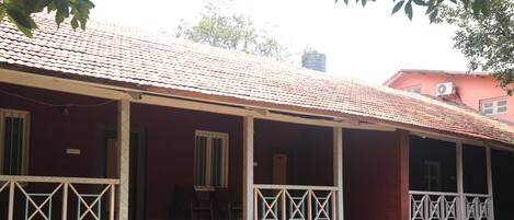 Um edifício com fachada vermelha, várias janelas com molduras brancas e um alpendre coberto com degraus que levam à entrada.