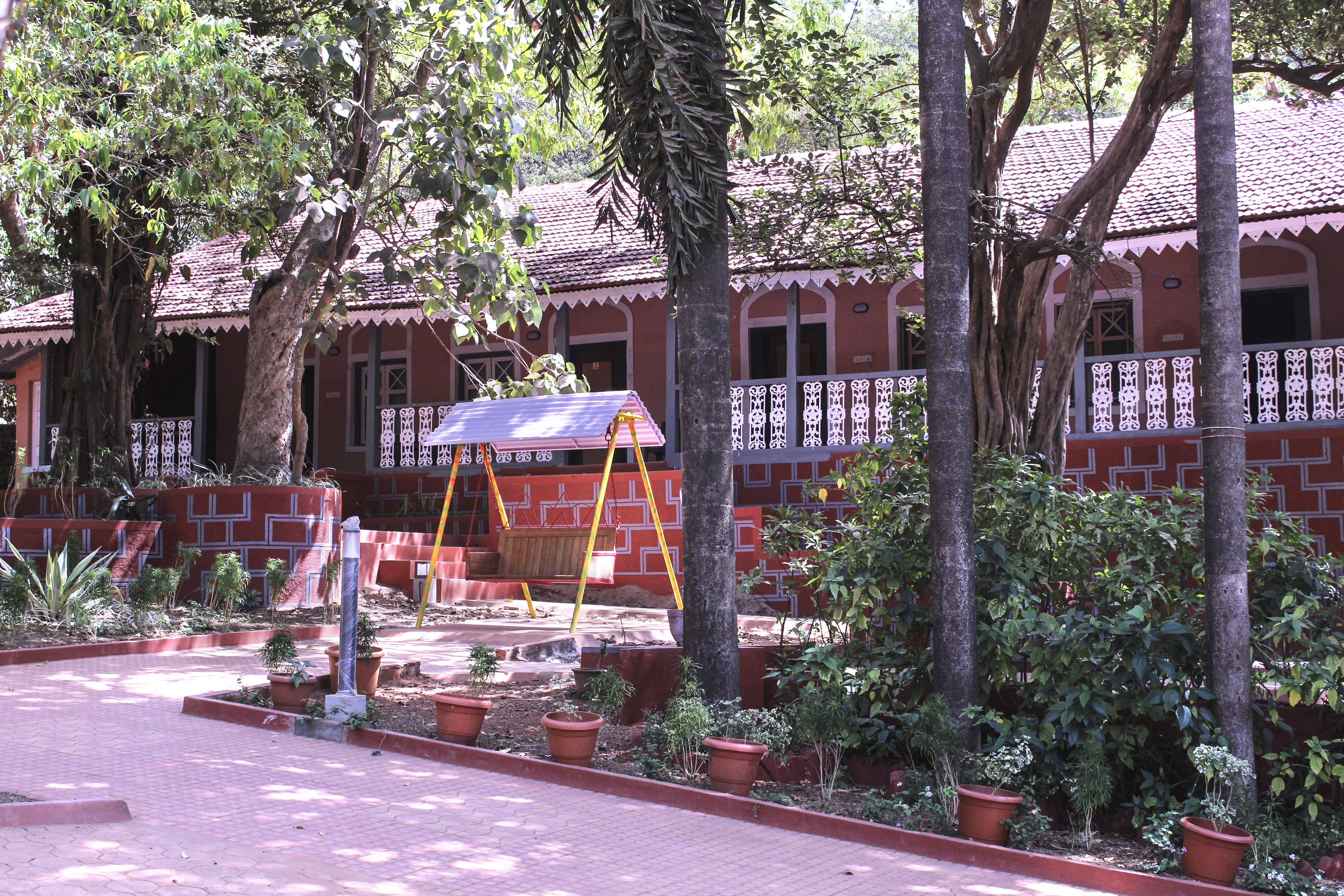 A courtyard with a swing set, potted plants, and a building with a tiled roof.