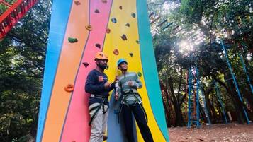 A person climbing a colorful rock wall with handholds and footholds.