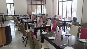 Un espace repas comprenant plusieurs tables et chaises, de grandes fenêtres et un aménagement propre et bien organisé.