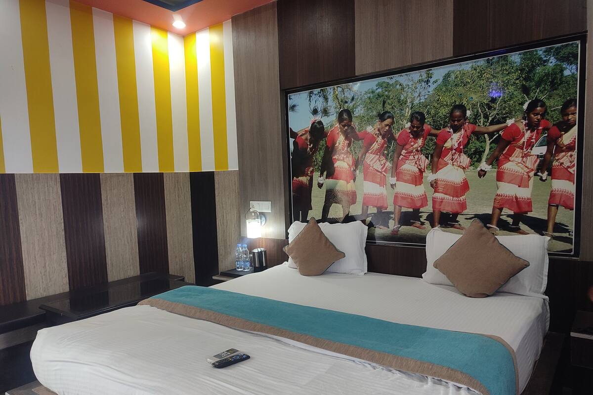 Quarto de hotel com uma cama grande, uma televisão na parede e um design de parede listrado.