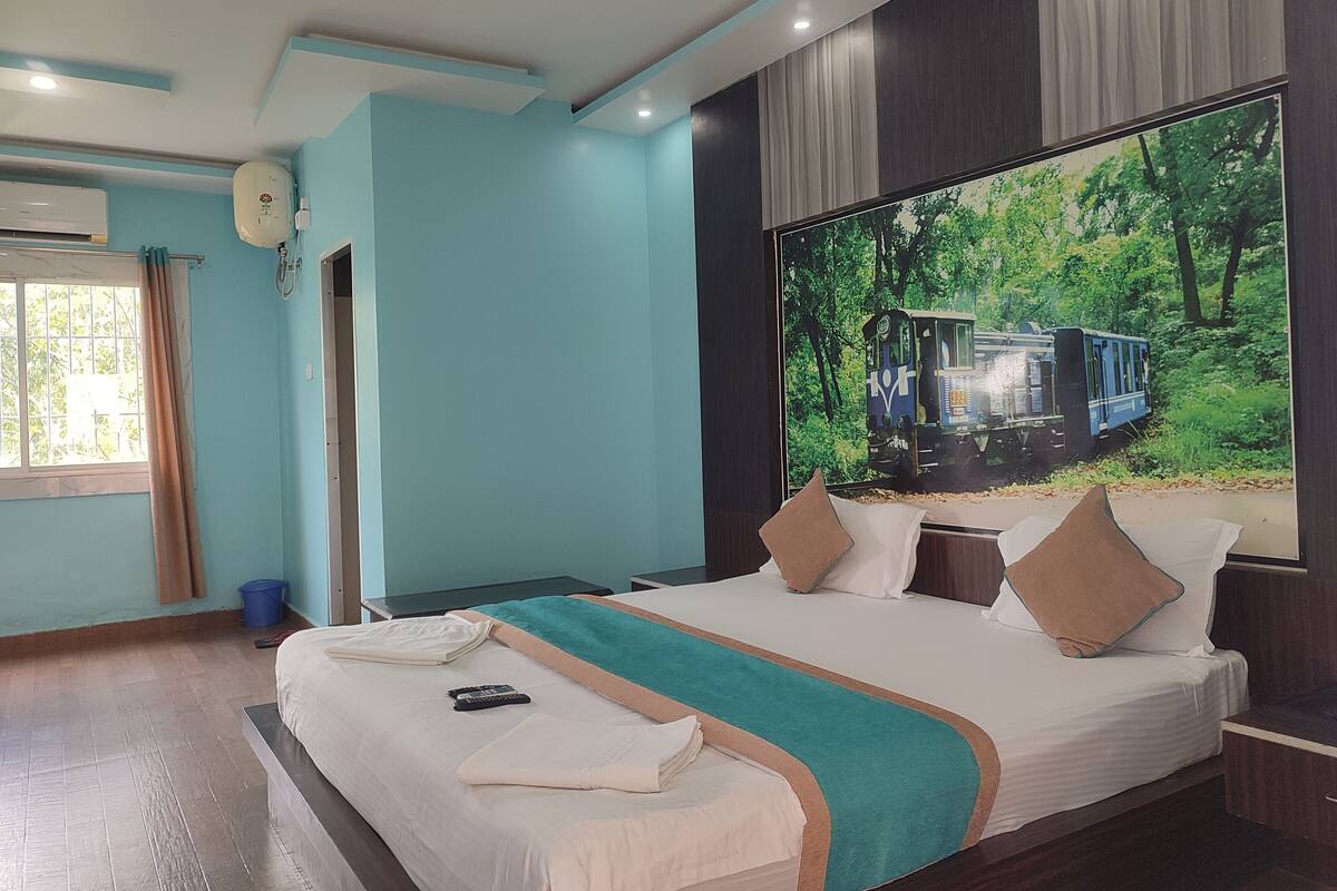 Quarto de hotel com uma cama grande, janela com cortinas, ventilador de teto e ar condicionado fixado na parede.