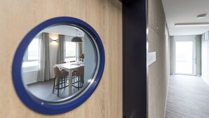 Un pasillo moderno de hotel con un espejo redondo que refleja una zona de comedor.