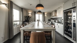 Una cocina moderna con una mesa comedor larga, un refrigerador y una lámpara colgante.