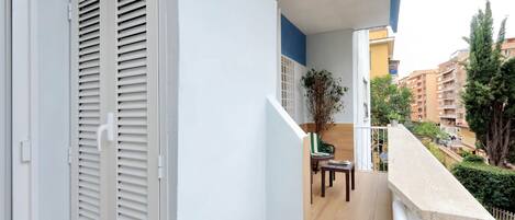A balcony with a wooden floor, a dining table with chairs, and a potted plant.
