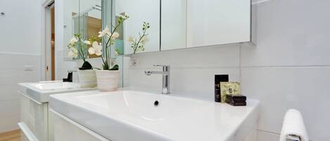 A modern bathroom with two sinks, a large mirror, and a potted orchid.