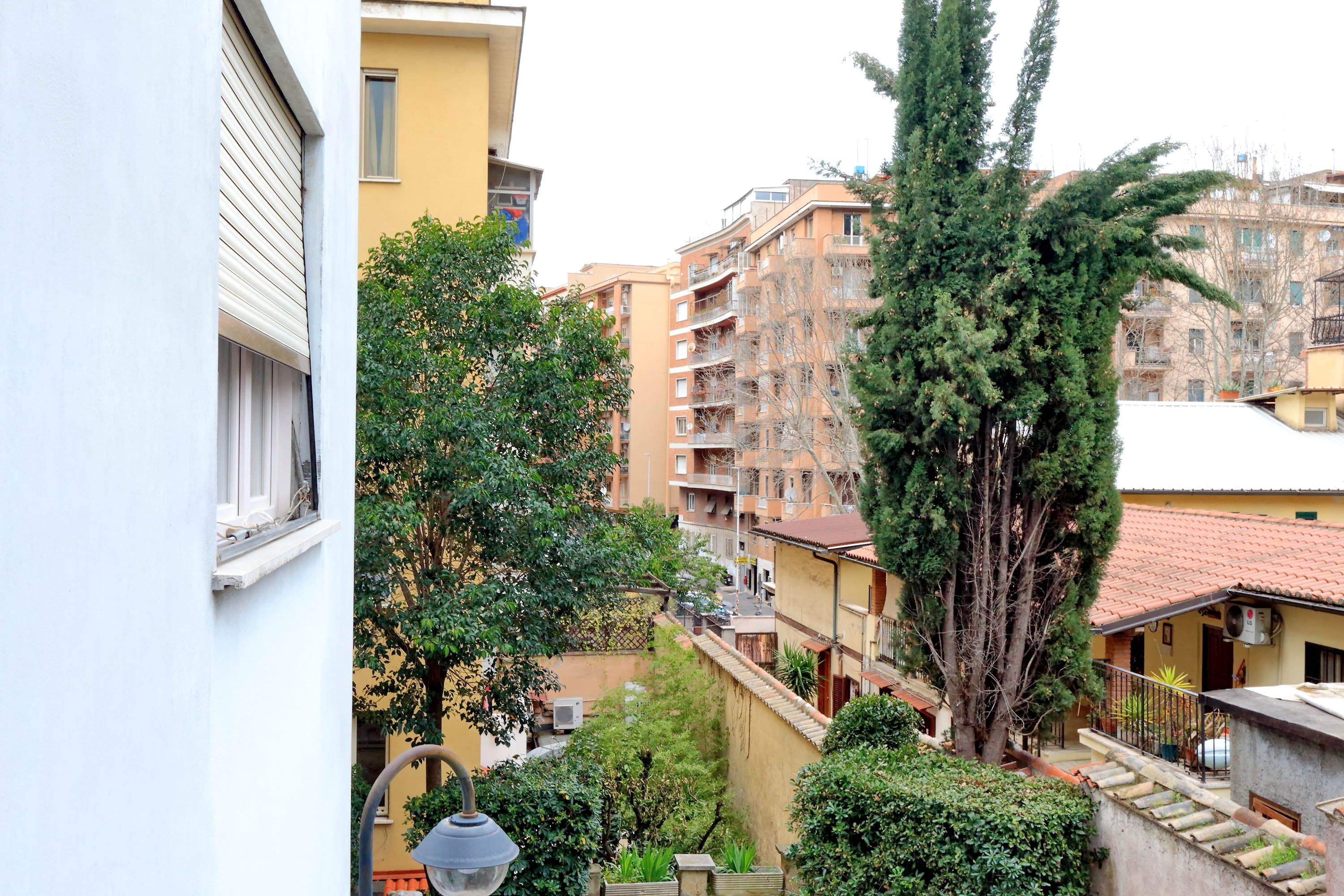 A residential building with balconies, a staircase, and a large tree.