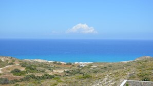 Paisaje costero con cielo despejado, una nube distante y vista al mar.