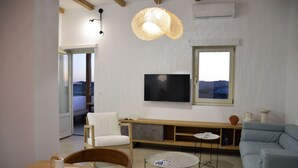 Una sala de estar moderna con televisor de pantalla plana, un sofá, una mesa de comedor y un ventanal con vistas.