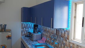 Eine kompakte Küche mit Kühlschrank, Mikrowelle, Wasserkocher und Spüle.