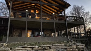 Ein zweistöckiges Gebäude mit Holzterrasse und Stein Fundament.