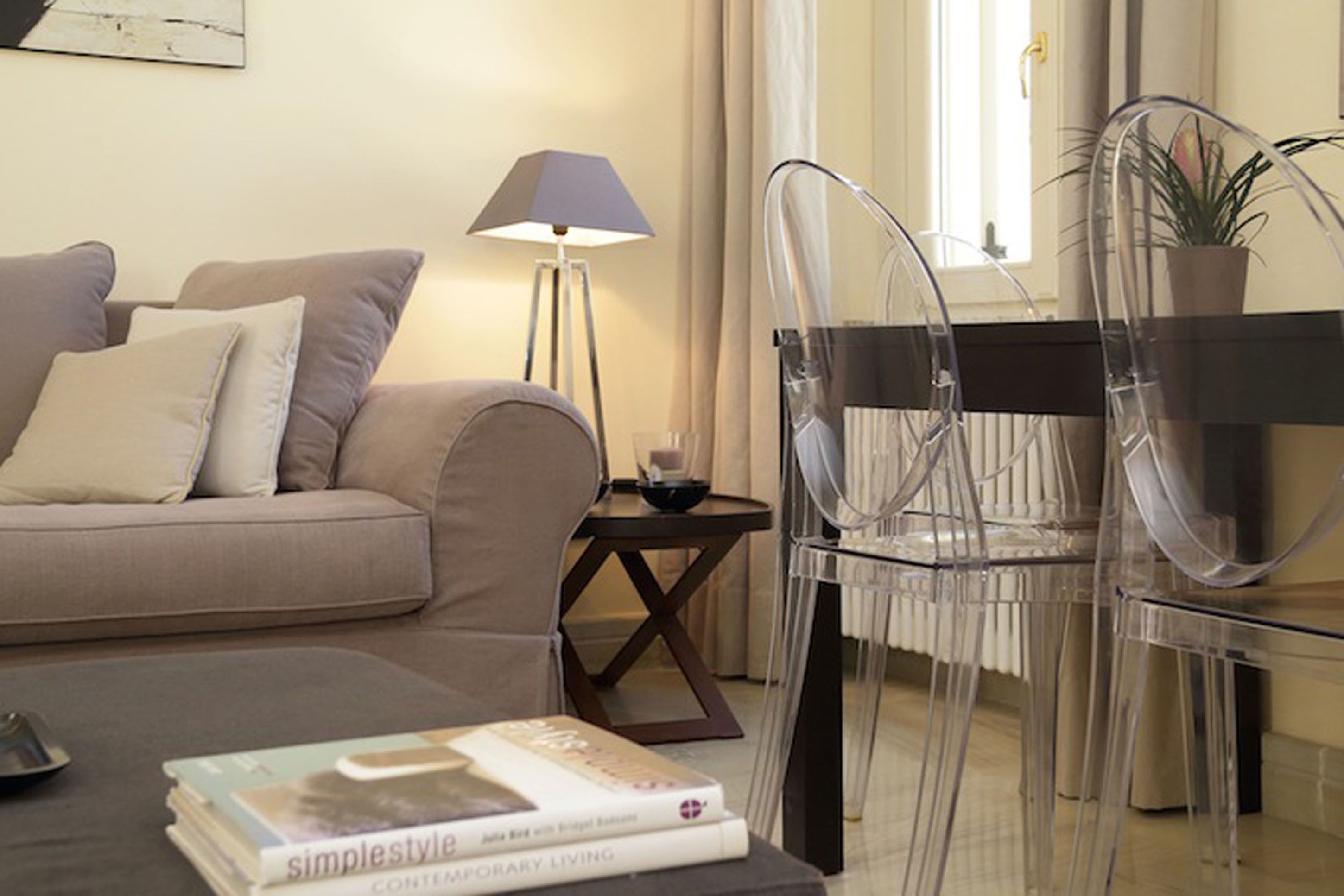A modern living room with a sofa, a glass table, and a chair.
