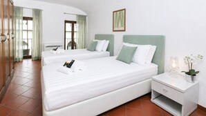 A hotel room with two beds, a nightstand, a potted plant, and a framed picture on the wall. - Fiorentini Charme - My Extra Home (Rome)