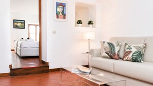 A modern living room with a sofa, a coffee table, a lamp, and a painting on the wall. - Fiorentini Charme - My Extra Home (Rome)