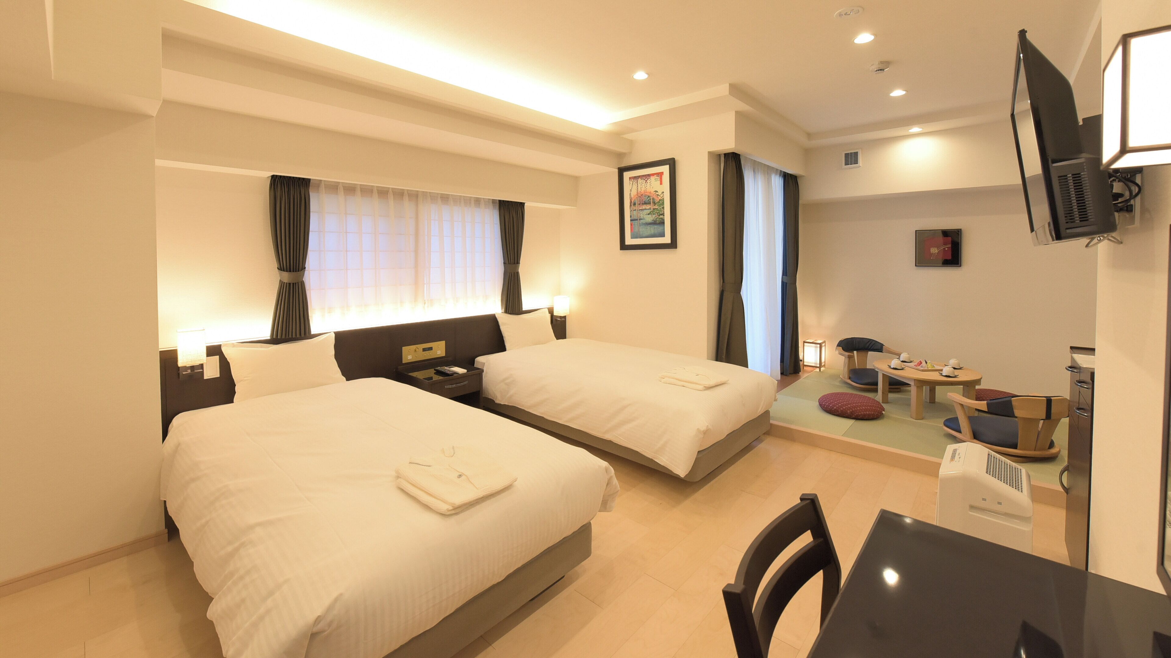 Une chambre d’hôtel avec deux lits, un bureau, une chaise, une télévision et un petit coin repas.
