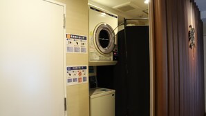 Habitación de hotel compacta con lavadora, secadora y un refrigerador pequeño.