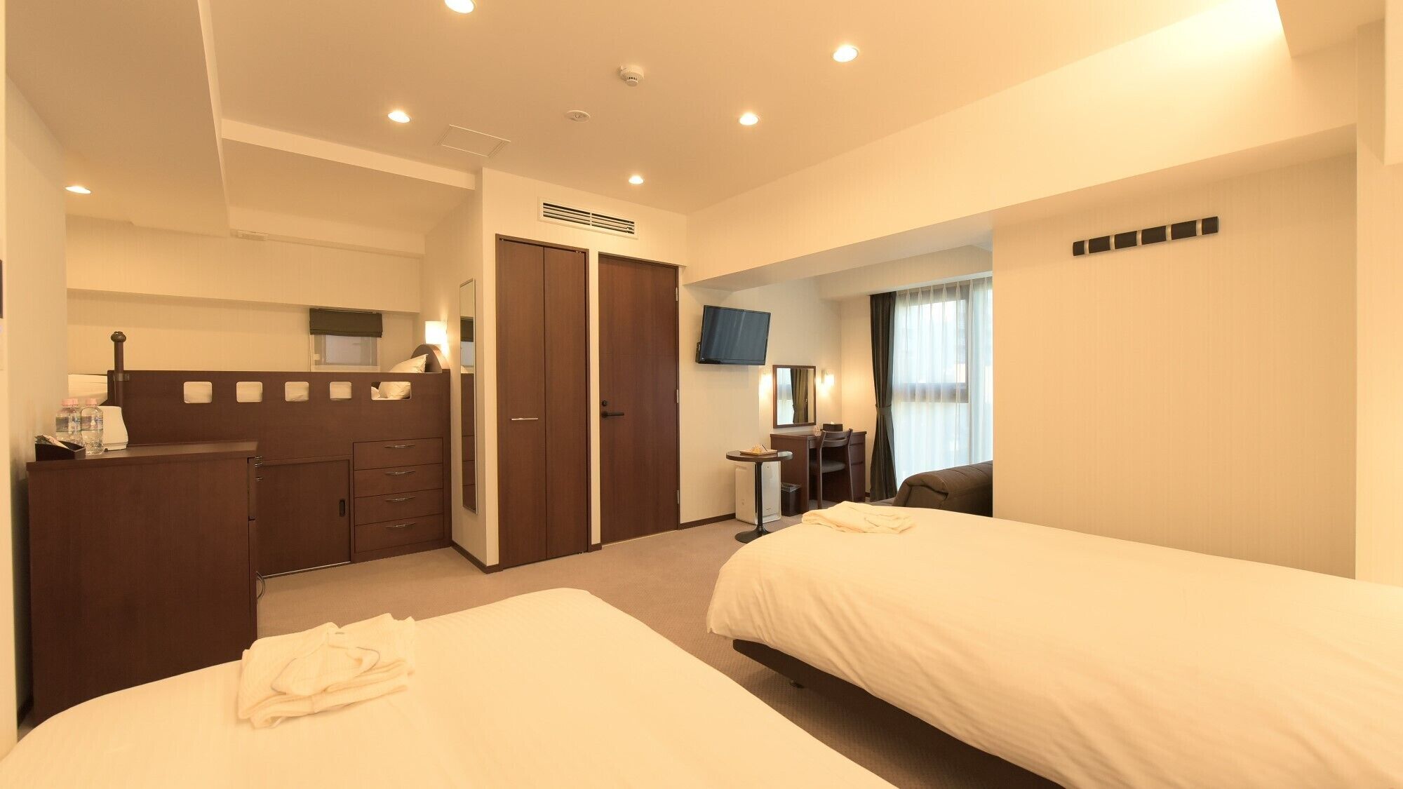 Une chambre d’hôtel avec deux lits, un bureau, une télévision et une armoire.