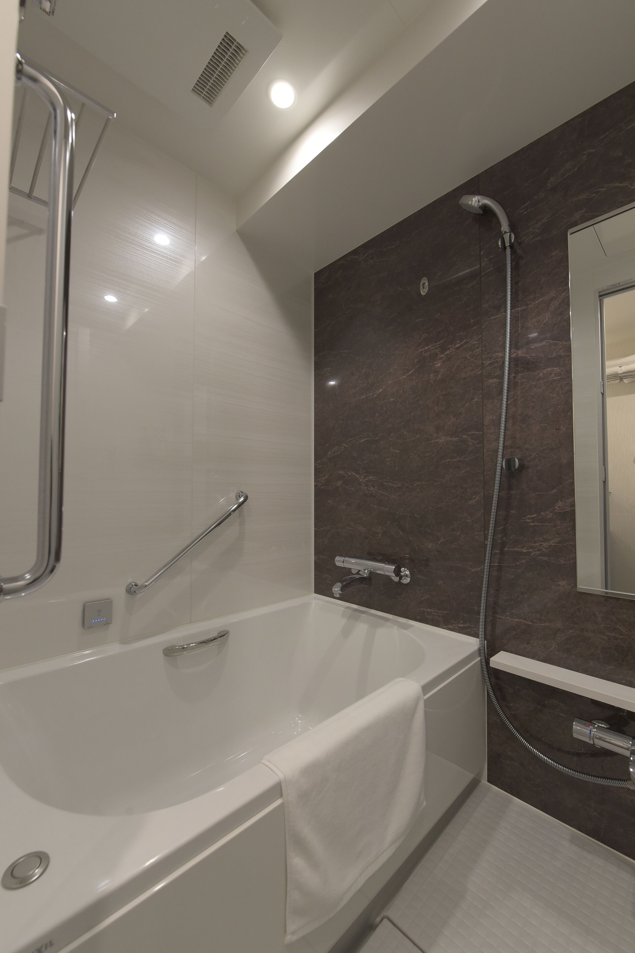 A modern bathroom with a bathtub, a shower, and a mirror.