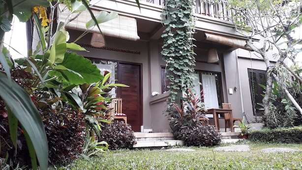 A two-story house with a balcony, surrounded by lush greenery and a well-maintained lawn. - Widi House (Ubud)