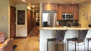 A modern kitchen with wooden cabinets, stainless steel appliances, and a central island with bar stools. - Book your Winter get away now (Avon)