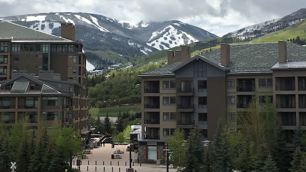 A hotel with multiple floors, a central courtyard, and a mountain backdrop. - Book your Winter get away now (Avon)