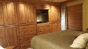 A bedroom with wooden cabinets, a bed, and a television. - Book your Winter get away now (Avon)