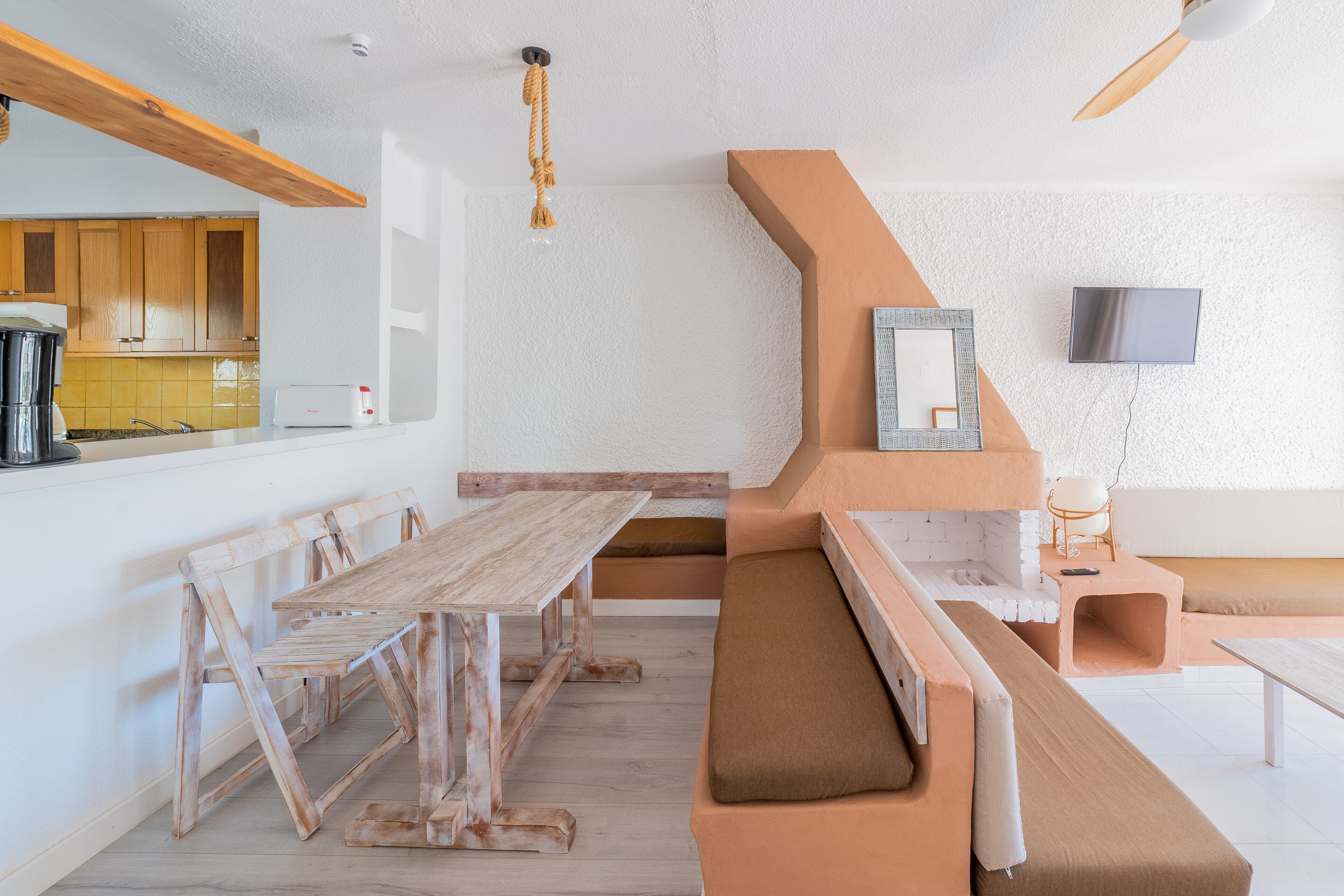 Una cocina moderna con armarios de madera, una mesa de comedor y un banco empotrado con cojines.