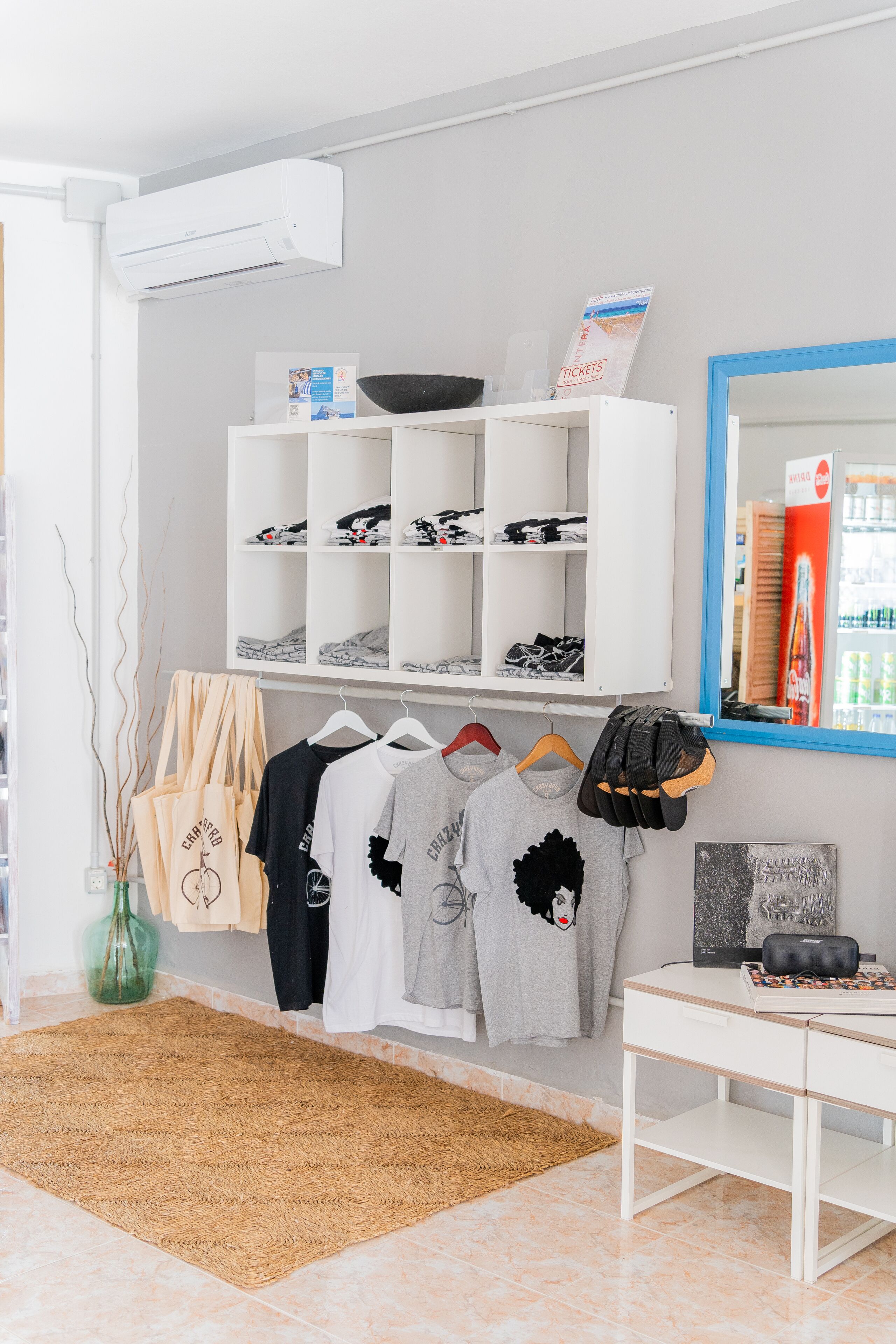 Une pièce avec un bureau blanc, des étagères remplies de chaussures et des vêtements suspendus.