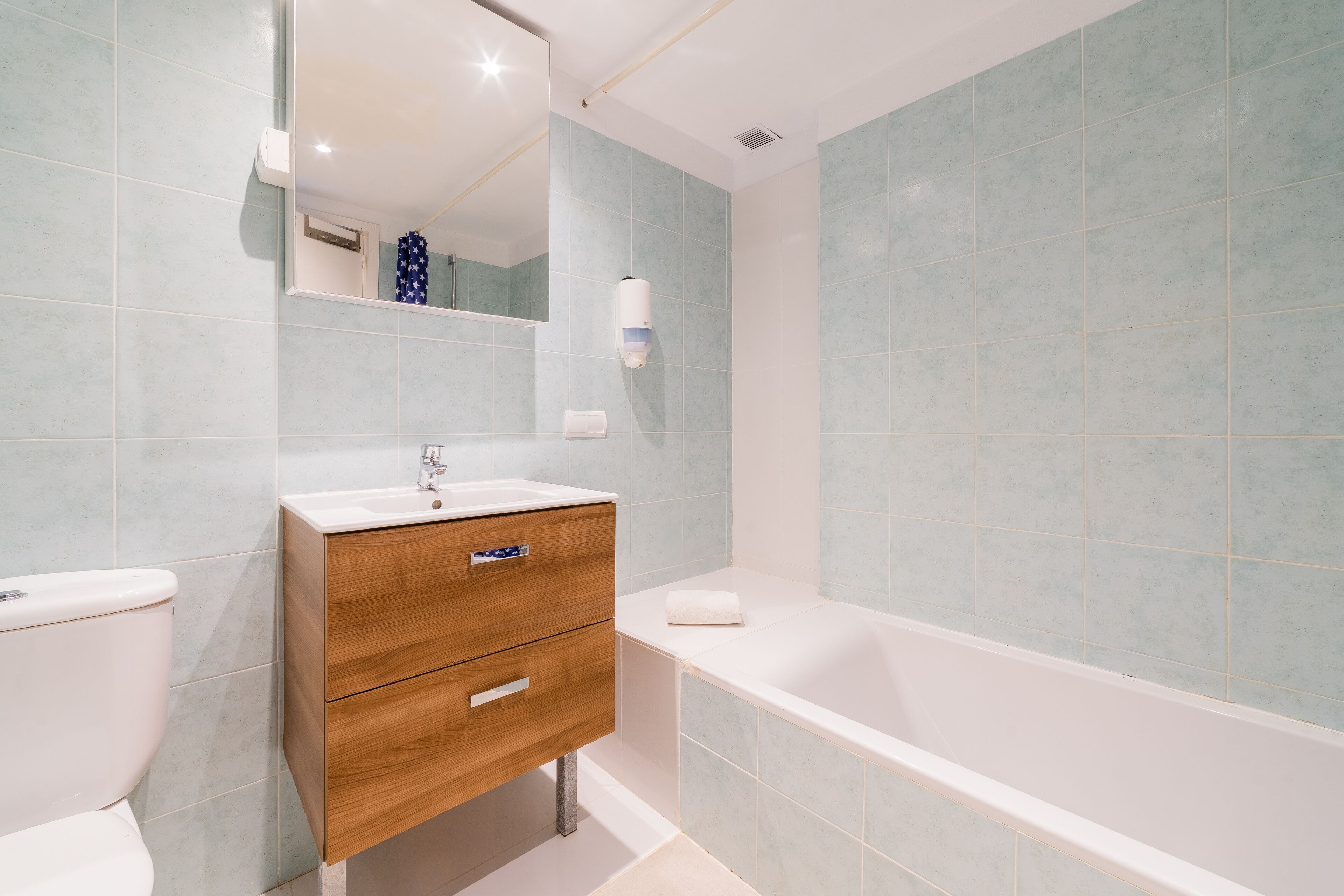 A bathroom with a wooden vanity, a white sink, a mirror, and a bathtub.