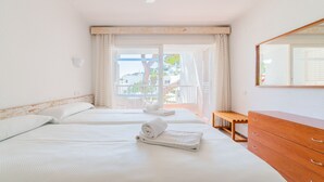 Een hotelkamer met twee bedden, een houten dressoir en een balkon met uitzicht.