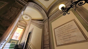 Un magnifique escalier, orné d’un lustre et d’une inscription encadrée sur le mur.