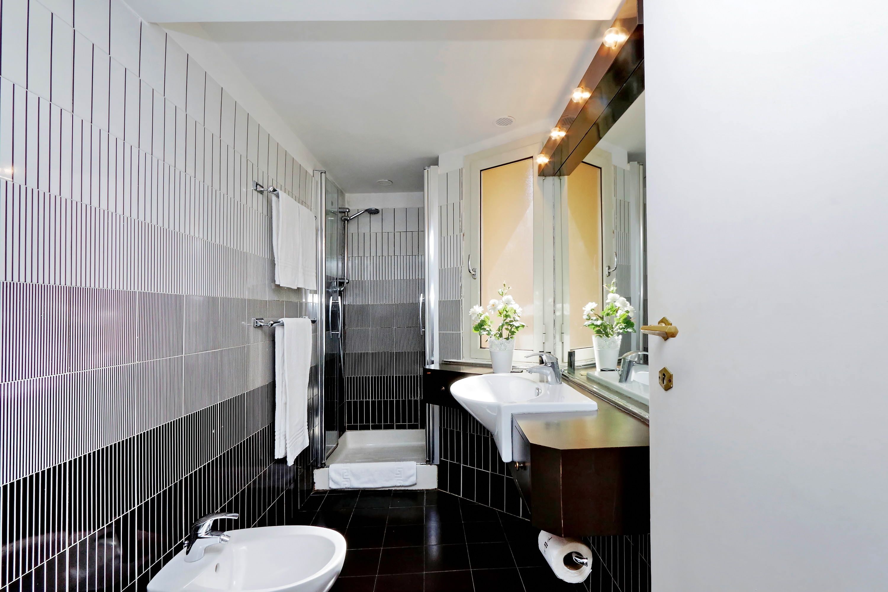 A modern bathroom with a walk-in shower, two sinks, and a large mirror.