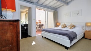 Une chambre à coucher avec un lit, une table de chevet en bois, une lampe et une vue sur l’extérieur.