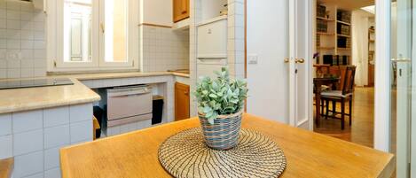 A kitchen with white tiles, wooden cabinets, and a dining area with a table and chairs.