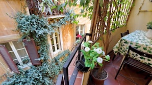 A balcony with a potted plant, a table with a tablecloth, and a chair. - Casa Navona - My Extra Home (Rome)