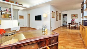 A spacious living area with a wooden coffee table, a bookshelf, and a dining table with chairs. - Casa Navona - My Extra Home (Rome)