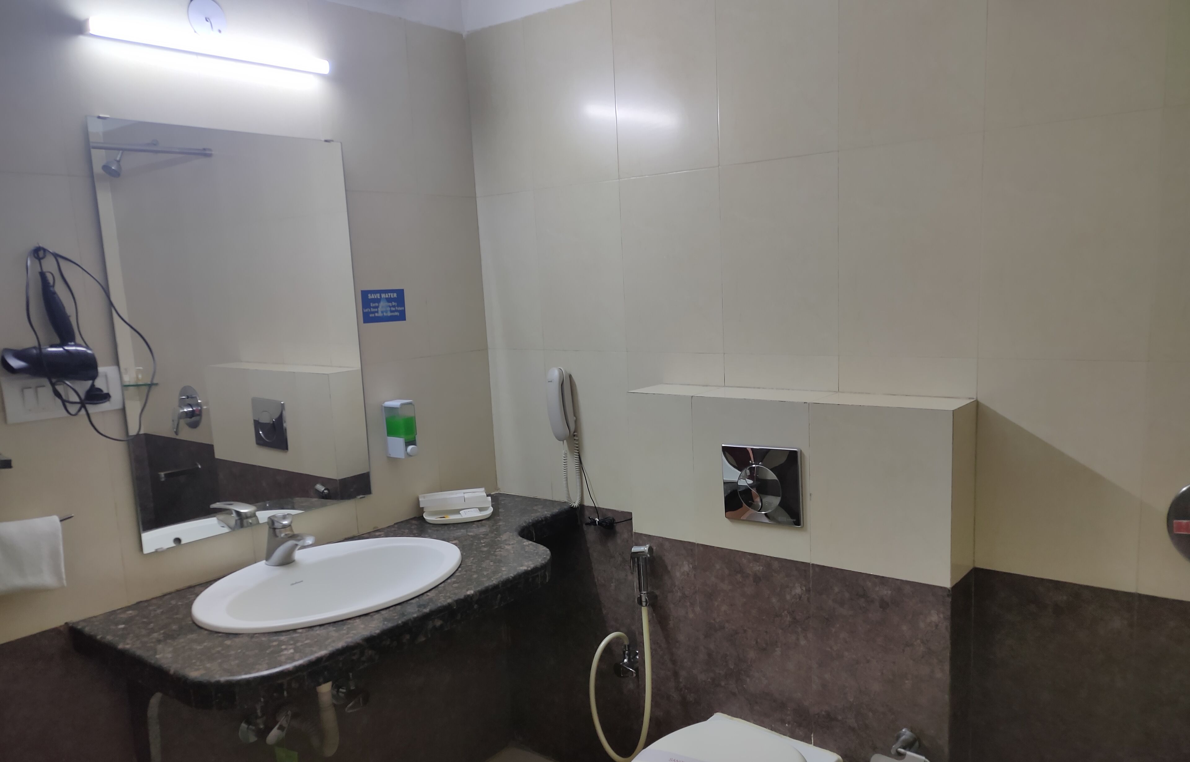 Une salle de bain équipée d’un lavabo, d’un miroir, d’un porte-serviettes et d’une douchette à main.