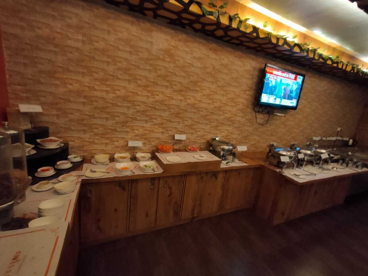 Een buffetopstelling met diverse gerechten en een aan de muur bevestigde televisie.