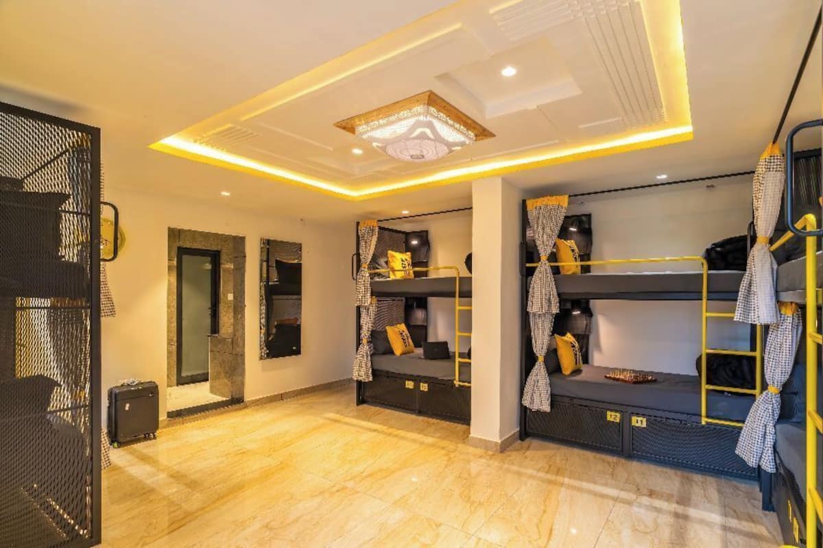 Une chambre d’hôtel moderne avec des lits superposés, un grand miroir et un luminaire décoratif au plafond.