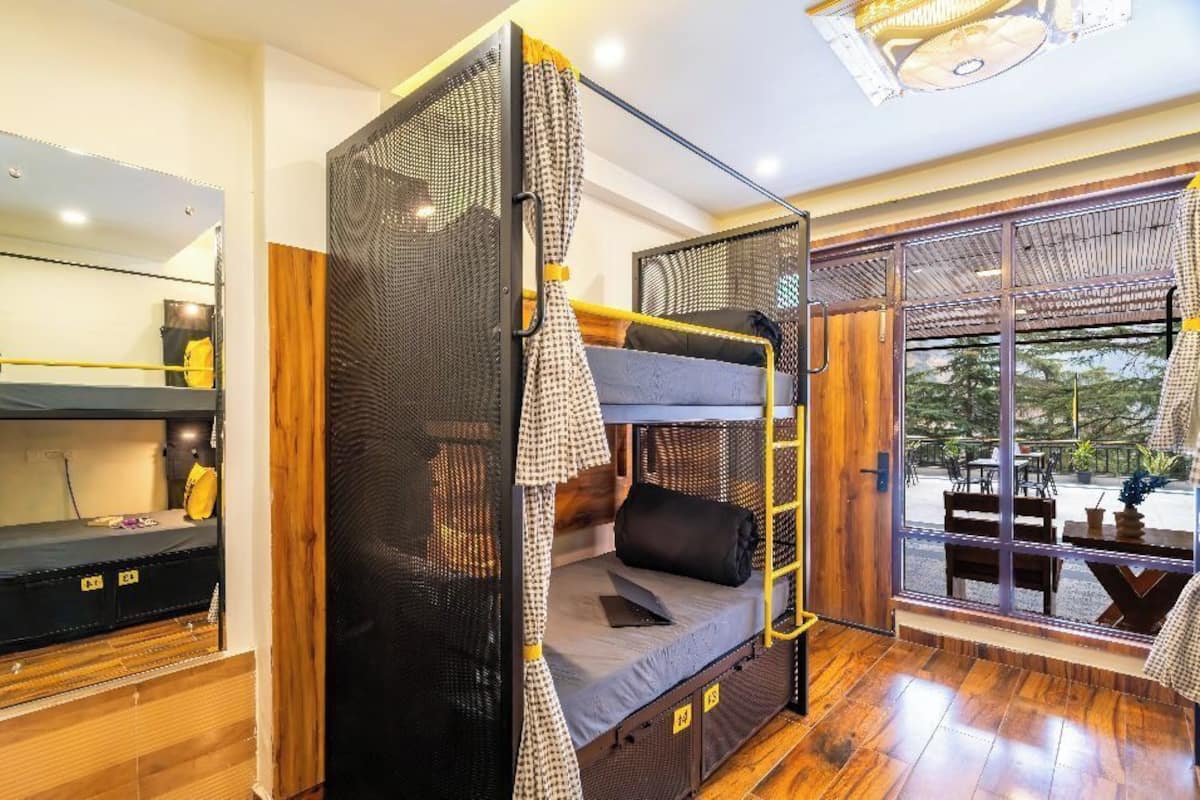 Une chambre avec un lit superposé, un miroir et une vue sur l’extérieur.