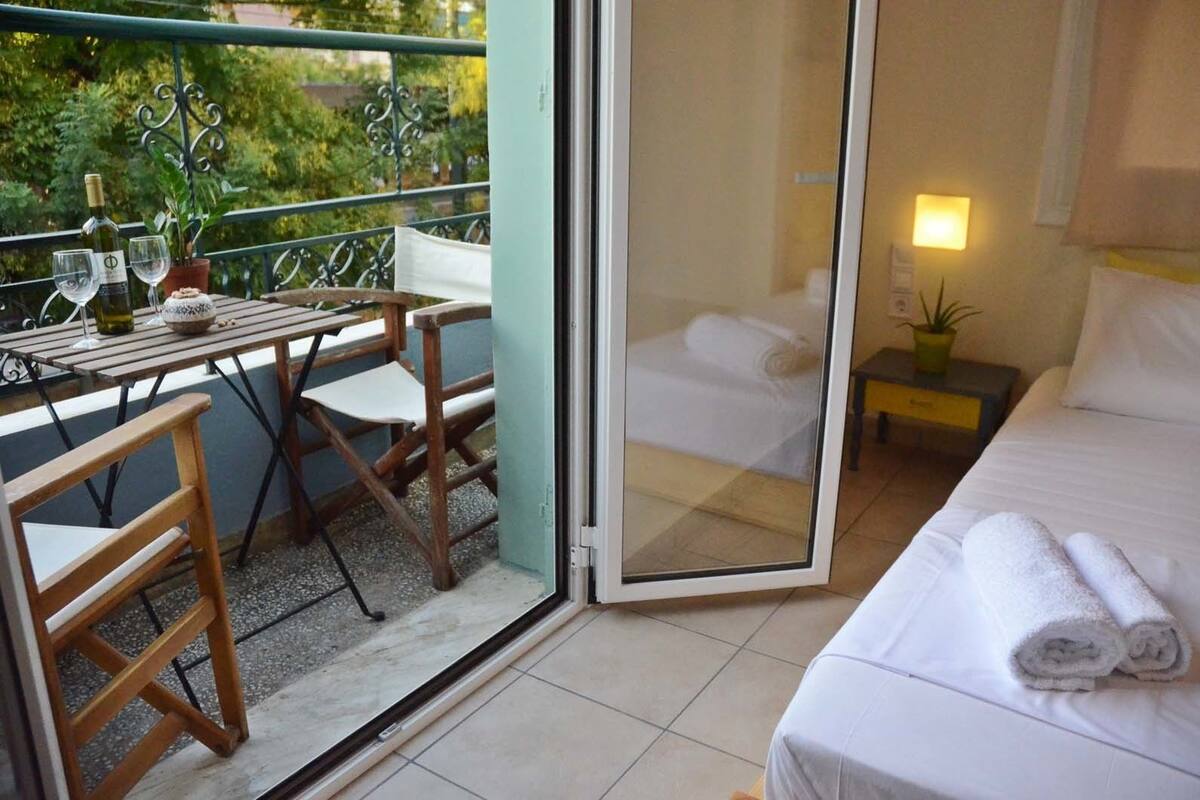 A balcony with a table, chairs, and a bottle of wine.