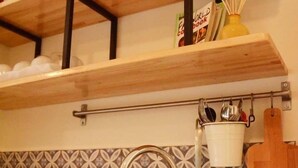 A kitchen with a stainless steel sink, wooden shelves, and a patterned backsplash. - Circle Inn (Athens)