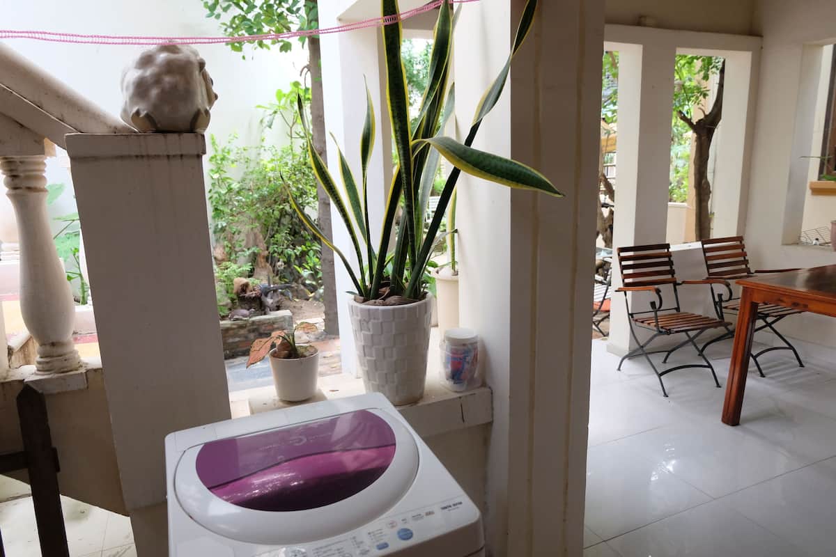 A laundry area with a washing machine, a potted plant, and a bench.