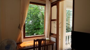 A room with a wooden table, a chair, a fan, and a window with curtains. - Moon House Nha Trang (Nha Trang)
